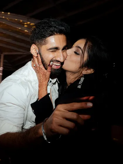 A playful and affectionate kiss on the cheek during the after-party. This candid shot shows the couple letting loose and enjoying the celebration after the formalities are over.
