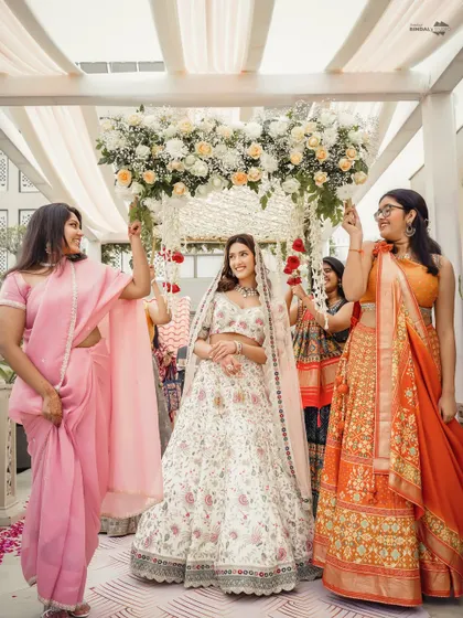 A modern and elegant bridal entry. The bride walks in with her bridesmaids under a beautiful floral canopy, a lovely twist on the traditional phoolon ki chaadar.