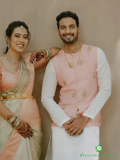 A portrait of the couple, highlighting the delicate gold embroidery on the groom's pink Nehru jacket. The details are designed to be visible and elegant both up close and from a distance.