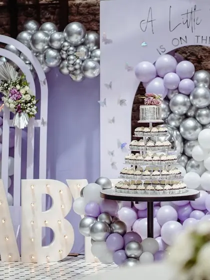 The full cake and decor setup, featuring a cupcake tower perfectly integrated into the lavender and silver butterfly-themed backdrop.