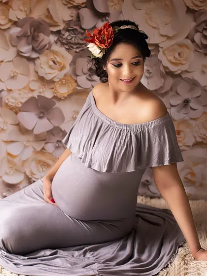 A serene portrait of a mother-to-be. The floral backdrop and soft lighting create a dreamy, romantic atmosphere that perfectly complements her gentle expression.