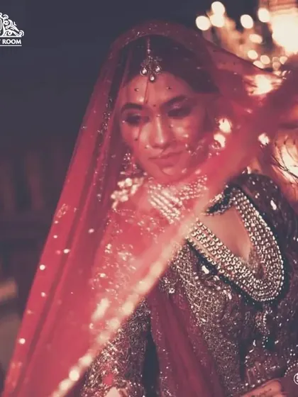 An ethereal shot of a bride behind her veil, with fairy lights adding a magical glow. The makeup is designed to look beautiful even in low and creative lighting.