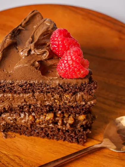 A slice of my Caramel Crunch cake. It features a moist chocolate sponge, 54% Belgian dark chocolate mousse, and crunchy caramel crisps, topped with fresh berries.
