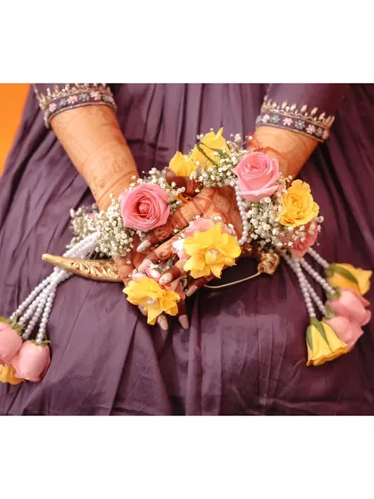 A close-up of the bride's hands adorned with beautiful floral kaleeras for her Haldi ceremony. We pay attention to every little detail.