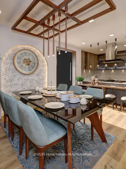 A stylish dining area from our Madurai project, featuring an arched, patterned wall niche, a dark glass-top table, and elegant blue chairs, all under a custom wooden ceiling light feature.