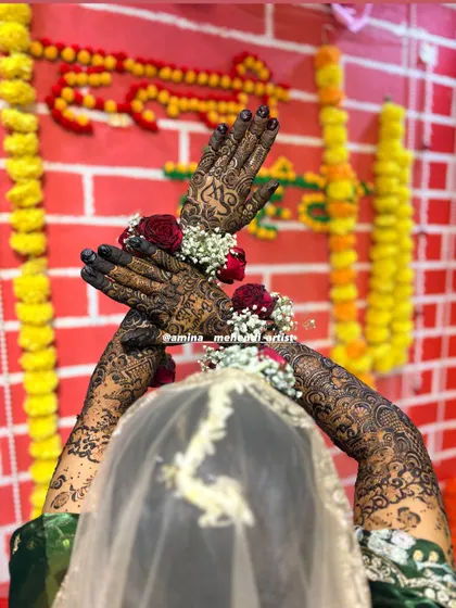 A beautiful shot from behind the bride, showing the full extent of the arm mehendi against a festive backdrop.