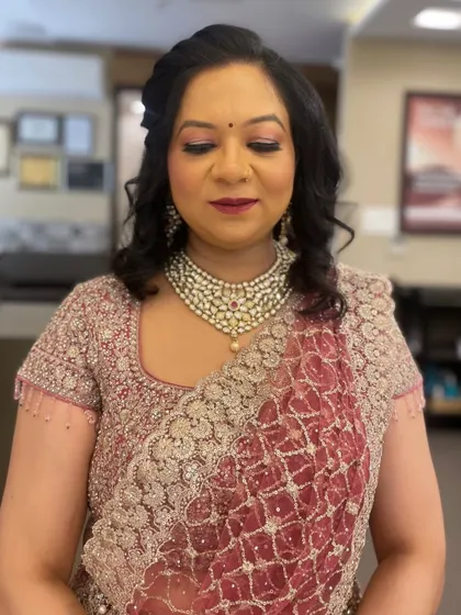 This is a classic party makeup look, perfect for a wedding guest or family member. The makeup features a soft shimmer on the eyes and a deep berry lip color that complements her embroidered saree.