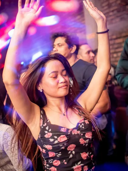 A guest dancing with pure joy, hands raised high at Roxy.