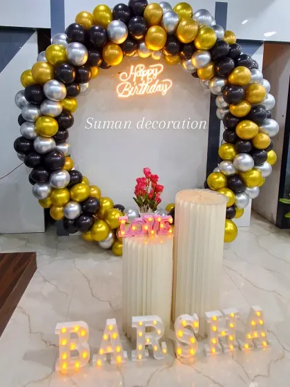 A stylish birthday setup with a black, gold, and silver balloon ring. The decor is personalized with the name 'Barsha' in marquee letters and a 'Love' prop.
