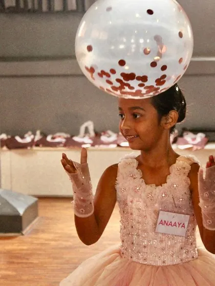 A student balances a balloon on her head during a game at our Nutcracker party. These events are all about fun, creativity, and play.