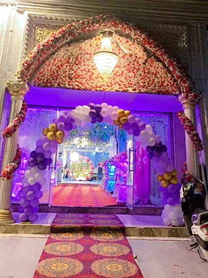 A beautiful balloon arch in purple, white, and gold creating a grand entrance to the banquet hall.