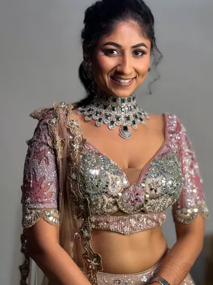 The bride looking confident and beautiful. The hairstyle is a chic ponytail, perfect for a modern reception lehenga.