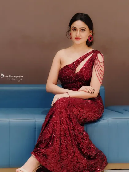 A full-length seated portrait of Sony Charishta, showcasing the stunning detail of her sequined red dress.