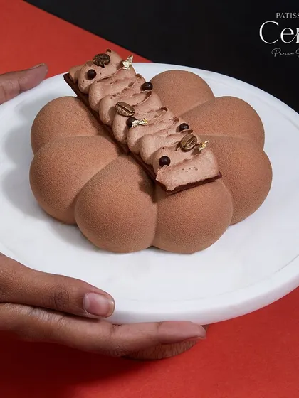 Here I am holding my Mochaccino entremet. It perfectly balances bold espresso with rich, creamy cocoa, offering an irresistible flavour profile and a slice of elegance with every bite.