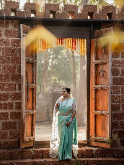 A sun-kissed bride in her beautiful turquoise saree. The natural light and lush green background make for a fresh and vibrant bridal portrait.
