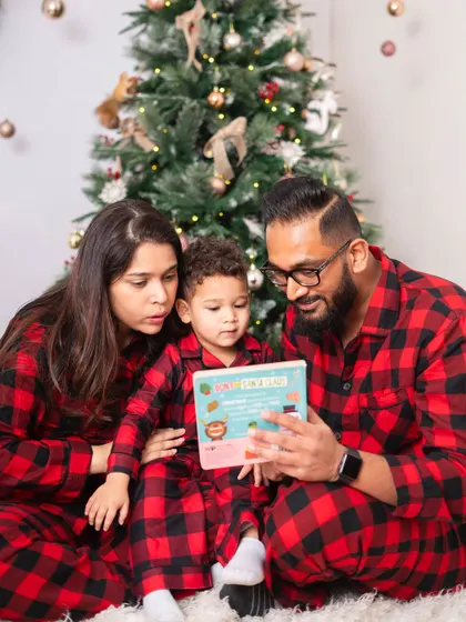 Reading a Christmas story together. An activity like this is a great way to get natural, interactive family portraits during a holiday session, creating memories of shared time.