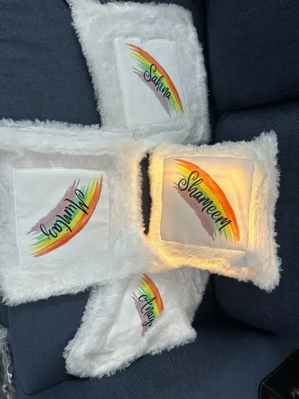 A set of four LED cushions with a rainbow and name design, some lit up and some not, to show the effect.