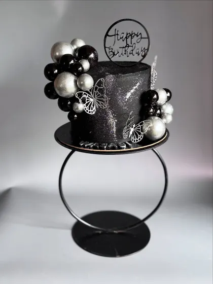 The shimmering silver details and delicate butterfly accents contrast beautifully against the sparkling black ganache.