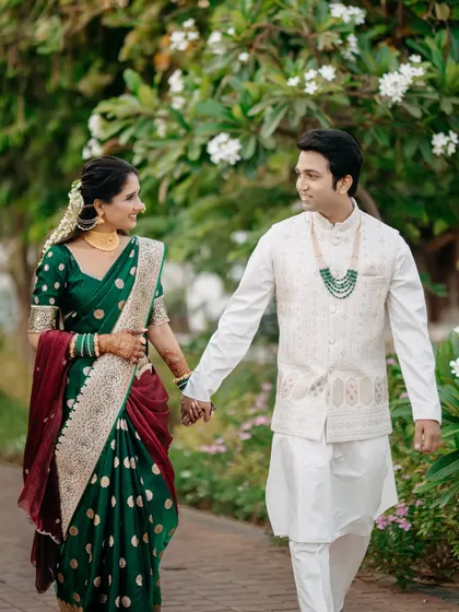 A candid moment of a couple walking hand-in-hand through a lush garden. Dressed in beautiful Maharashtrian attire, their shared glance speaks volumes, reflecting the natural, unscripted joy I love to capture.