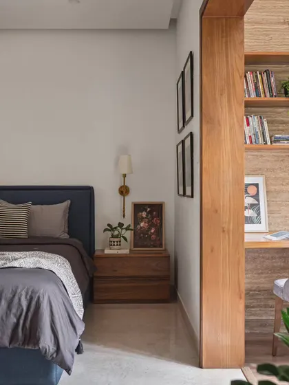 A view of the transformed bedroom, showing the new bed with a deep blue headboard and the cozy study nook in the background. The warm wood tones of the furniture and partition create a cohesive and inviting space.