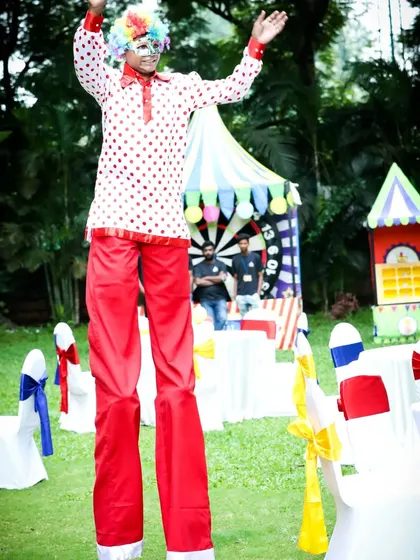 A stilt walker entertains guests, towering over the party and adding to the festive carnival vibe.