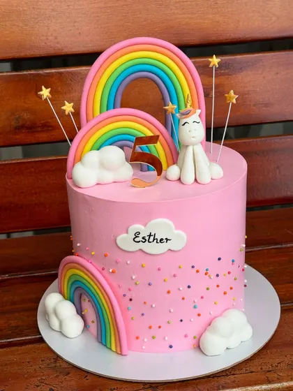 This pretty pink unicorn and rainbow cake is one of our most requested designs. It features handmade fondant rainbows, clouds, and a cute unicorn, finished with colorful sprinkles for a touch of magic.