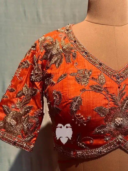 A close-up of the orange blouse, showing the zardosi magic in the center of the flowers.