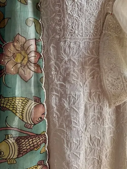 A close-up on the sleeve and side of the kurta, showing the placement of the Chikankari embroidery and the delicate, shimmering highlights on the hand-painted Kalamkari dupatta.