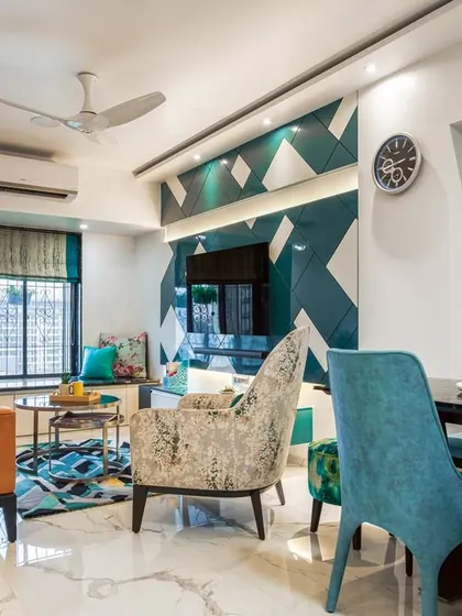 The living room is a bold statement with a geometric teal accent wall behind the TV, paired with a burnt orange sofa for a striking color contrast.