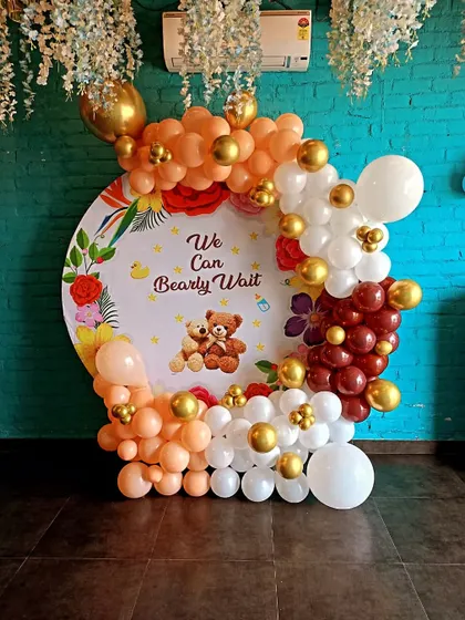 A "We Can Bearly Wait" baby shower with an orange, white, and brown balloon arch around a custom backdrop.