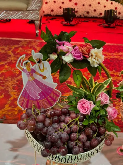 A silver bowl of fresh grapes decorated with a cutout of a dancing couple. This adds a fun and personal touch to a fruit platter for a half-saree function or sangeet.