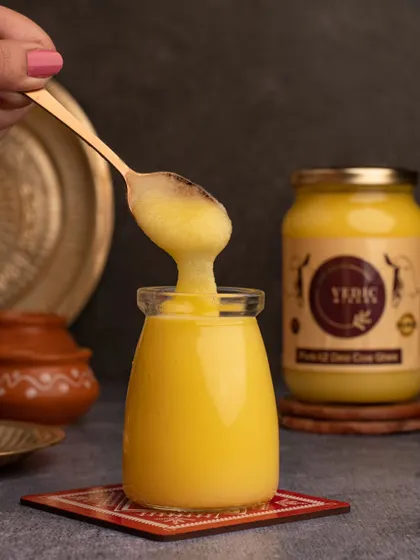 An action shot showing the rich, granular texture of the Vedic Wisdom ghee. This image focuses on the product's quality, making it look pure and wholesome.