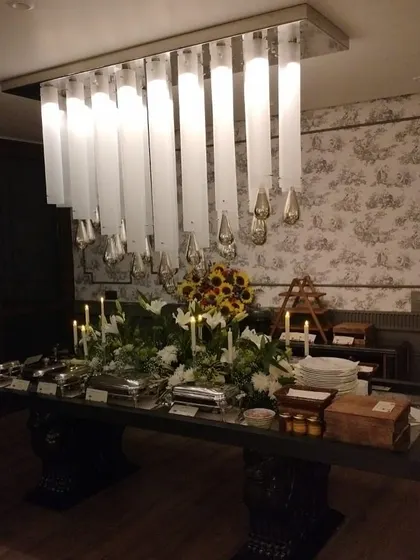 A wide shot of the same elegant buffet under a modern chandelier. This shows how I can adapt my setups to complement the decor of any home or venue.