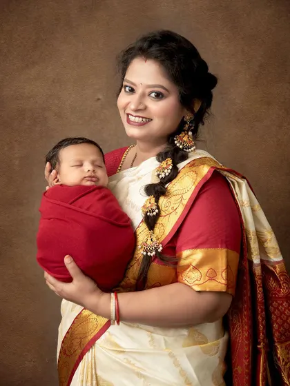 A proud mother in a traditional South Indian saree holds her sleeping newborn. This portrait is a beautiful blend of cultural heritage and the timeless love for a new child.