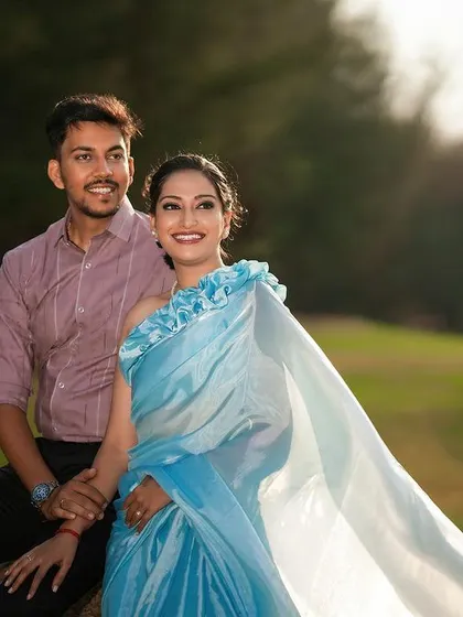 A bright and happy portrait of a couple in a sunlit field, the light catching the bride's saree perfectly.