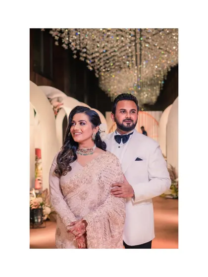 A classic portrait of the couple at their pre-wedding reception. The stunning crystal chandelier and their elegant attire create a look of pure sophistication.