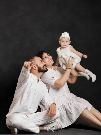 Where every smile becomes a story. This joyful family portrait against a simple dark backdrop makes their happiness the true focus.