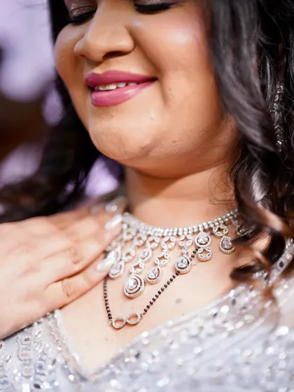 A close-up on the details. The soft pink lip and shimmering eyeshadow complement the intricate diamond necklace and mangalsutra.