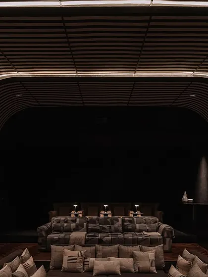 A glimpse into the moody and luxurious home theatre at Rehethaan, designed for an immersive cinematic experience with plush, comfortable seating.