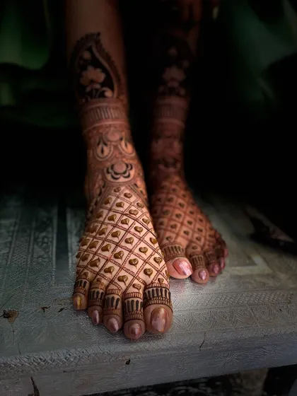 A beautifully composed shot of a bridal foot mehandi with a heart-filled jaali pattern, showing the rich dark stain.