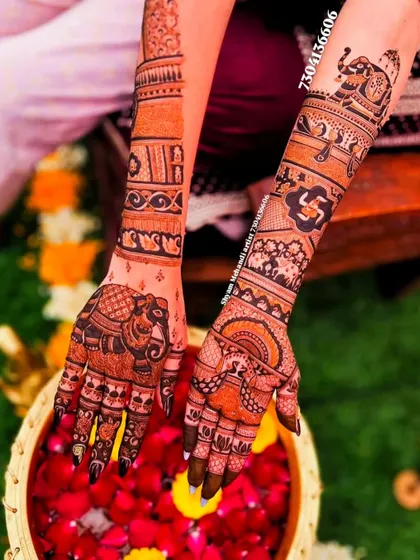 A view of both hands, one with a large elephant design and the other with intricate traditional patterns.