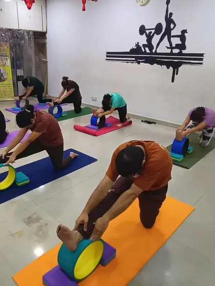 Our students using yoga wheels and blocks to modify Janu Sirsasana (Head-to-Knee Pose). This setup helps to stretch the hamstrings and side body more effectively while maintaining a long spine.