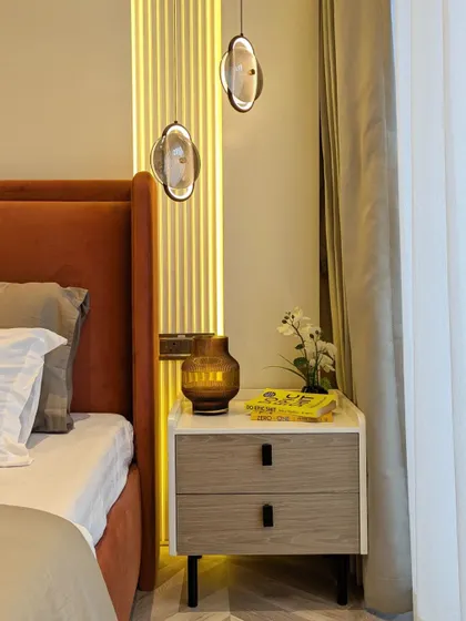 A close-up of a bedroom's accent wall, featuring a fluted panel with integrated vertical lighting that creates a warm and sophisticated ambiance.