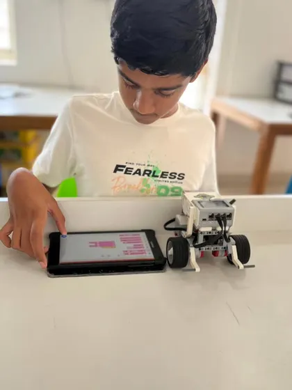 A student makes final adjustments to his code on a tablet before running his LEGO robot. This iterative process of coding, testing, and refining is fundamental to robotics.