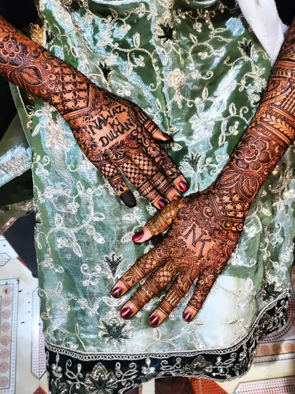 A special bridal design featuring the groom's initial 'N' on one hand and the bride's initial 'K' on the other, along with the phrase 'Nawaz ki Dulhan' (Nawaz's Bride).