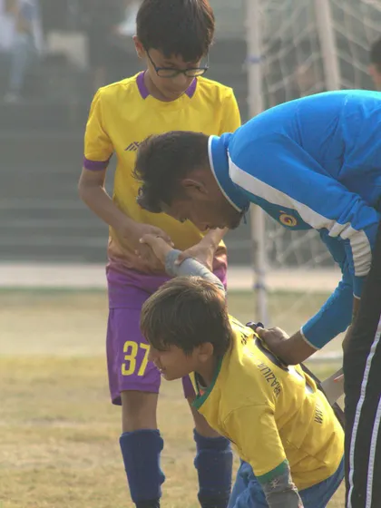 A coach offers a hand to a player who has fallen, a small moment that shows the sportsmanship and supportive culture we foster. It is about competing hard and respecting your opponents.