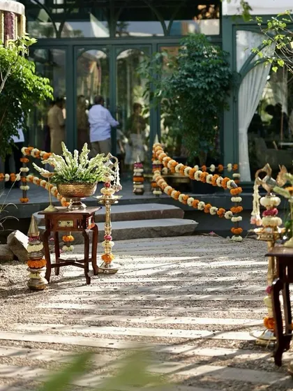 A traditional welcome path at a garden venue, lined with marigold garlands and brass decor.