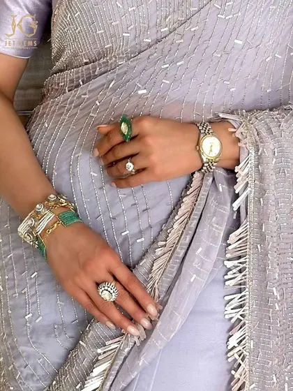 Every detail tells a story of elegance. Here, a stack of emerald bracelets and rings adds a vibrant touch of colour to a classic ethnic look.