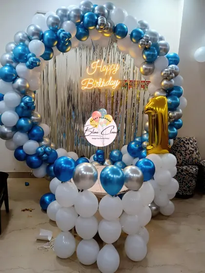 A full balloon ring in blue, white, and silver with a shimmer curtain for a first birthday.