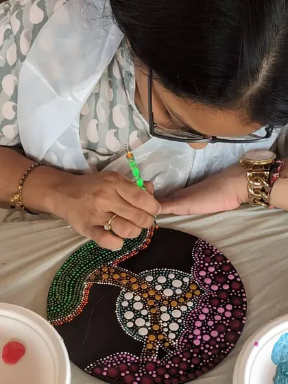 A close-up of a participant creating a dot mandala, carefully placing each dot to form a symmetrical pattern.